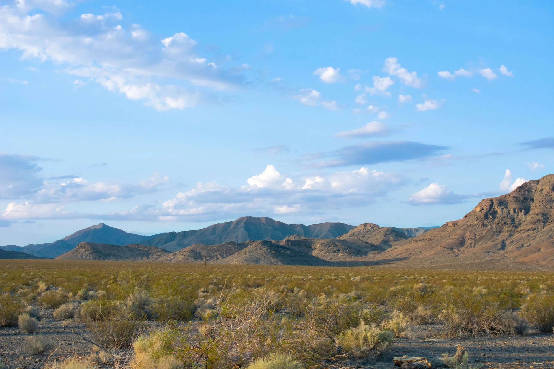 Landscape of mountains and sagebrush with a warm and sunny sky.